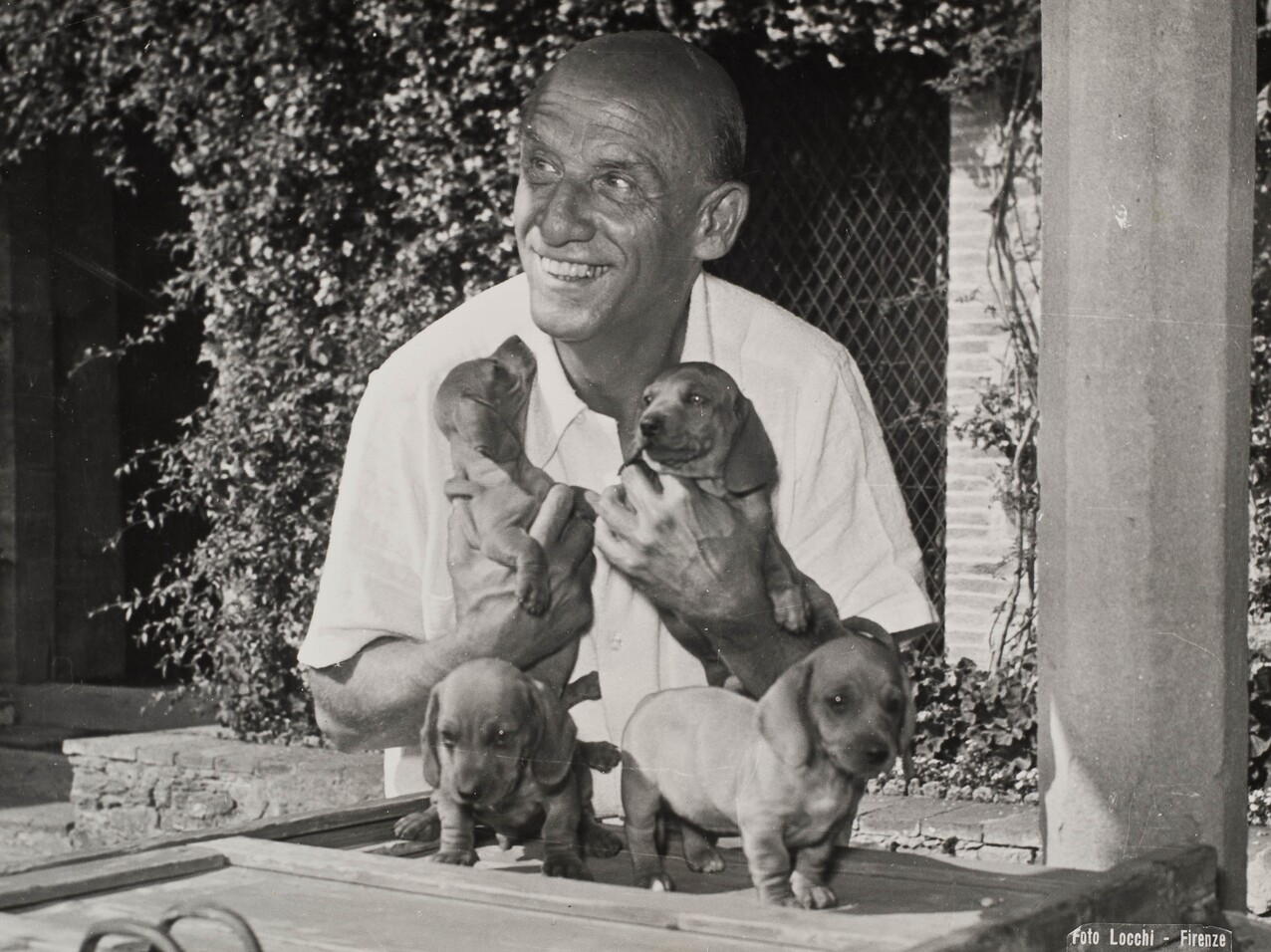 Dimitri Mitropoulos smiling and holding puppies.