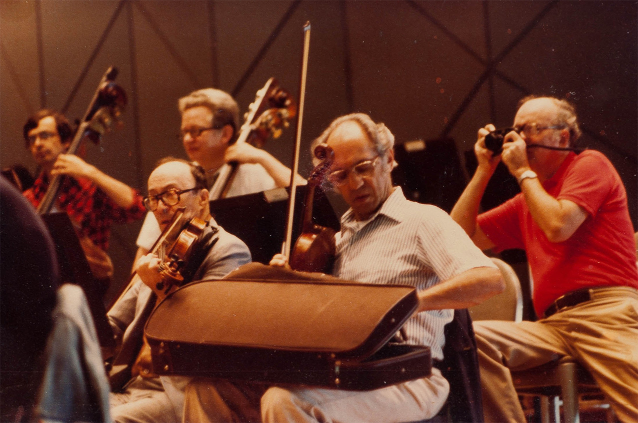 Bert Bial, right, snaps a shot of his string-playing colleagues before rehearsal starts.