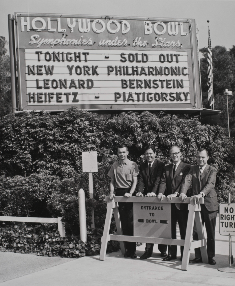 Philharmonic staff members pose in front of a Hollywood Bowl sign indicating a sold-out performance.